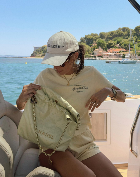 light yellow chanel 22 bag on a girl wearing a sporty and rich two piece set on a boat in the middle of the sea