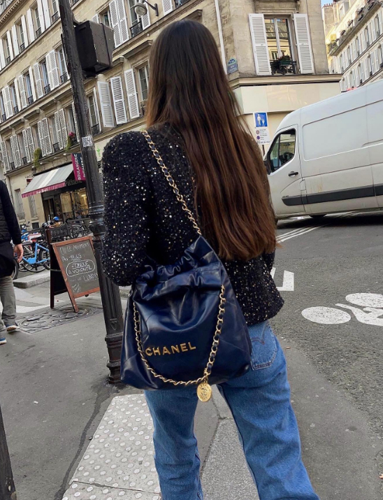 Girl walking through the streets of Paris wearing a navy Chanel 22 bag and tweed jacket