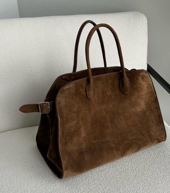 the row margaux velvet 15 bag on a boucle chair