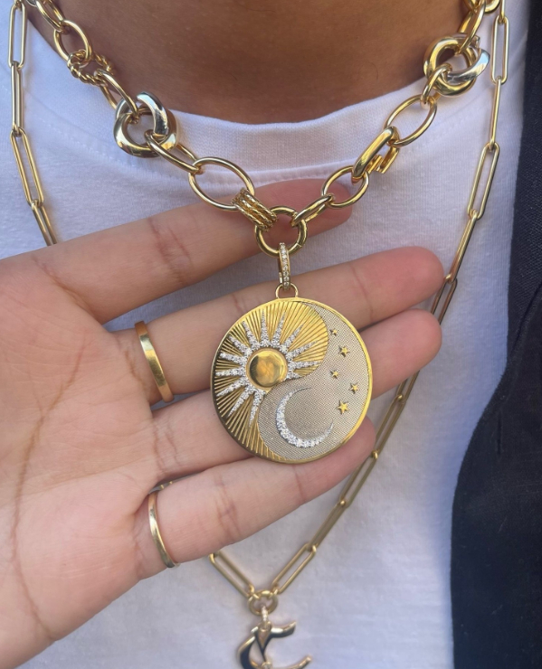 Person holding up a FoundRae Sun and Moon Pendant