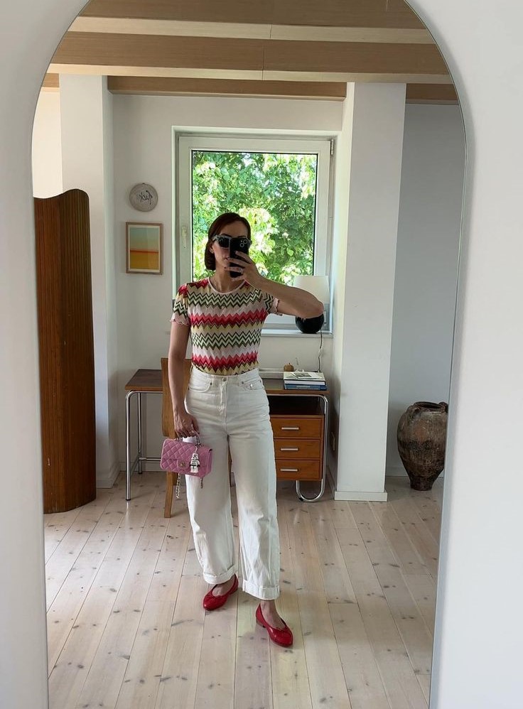 Woman wearing Missoni top with white jeans and red chanel ballet flats