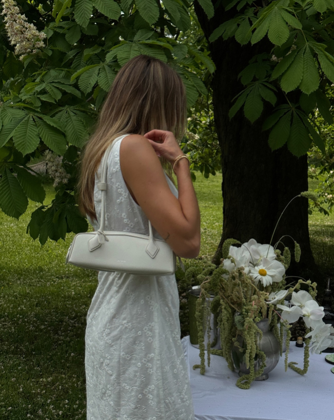 Person carrying Alaïa Le Teckel Bag in white