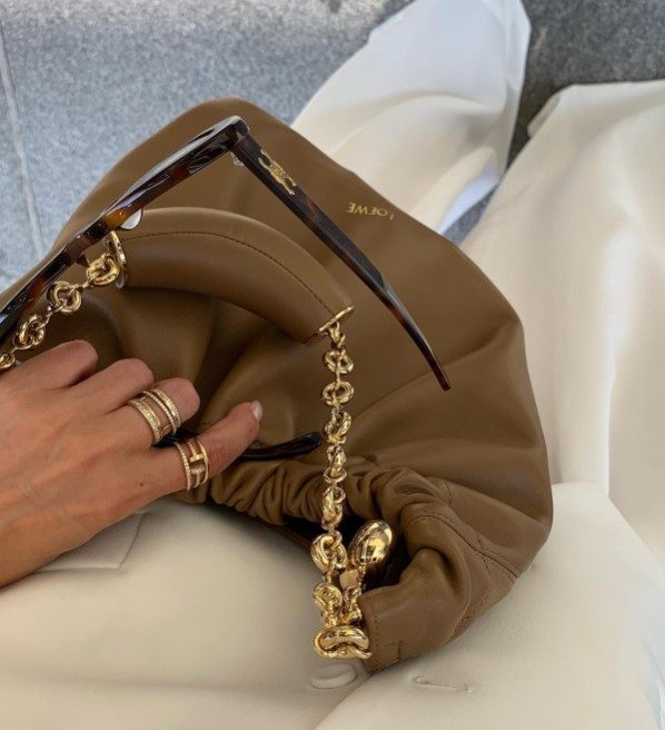 Someone holding a Loewe Squeeze Bag with Celine Triomphe Sunglasses