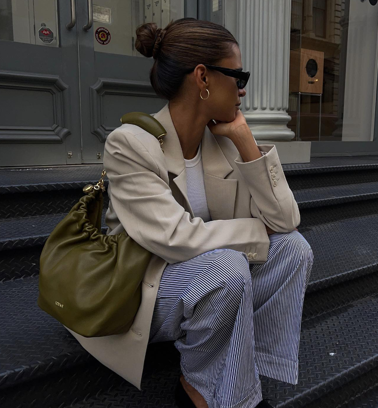 The green Loewe Squeeze Bag casually worn on the shoulder in the city