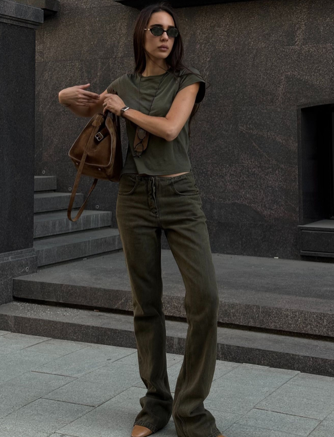 A brown Suede The Row Margaux bag being carried under the arm as a clutch